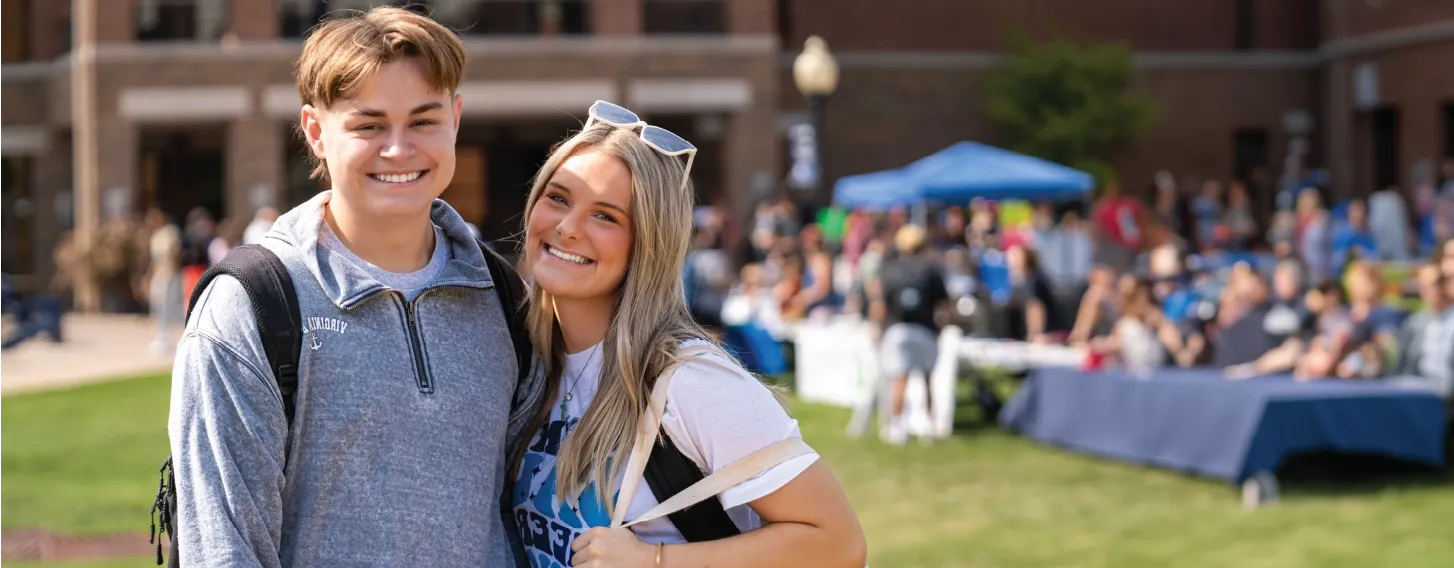 Two students smiling together outdoors during fair.